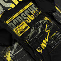 Black T-shirt laid flat with natural fabric folds, featuring Porsche 911 Turbo S rs 911 turbo racing german street classic graphic.