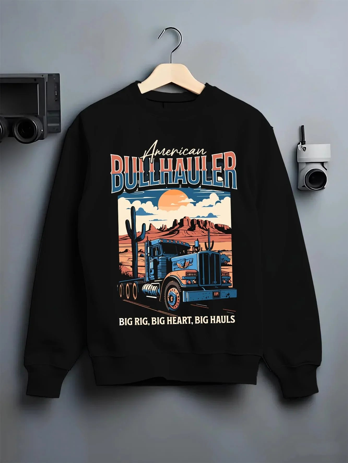 Black crewneck sweatshirt on a hanger against a grey wall, featuring american street classic racing performance motorsport graphic.