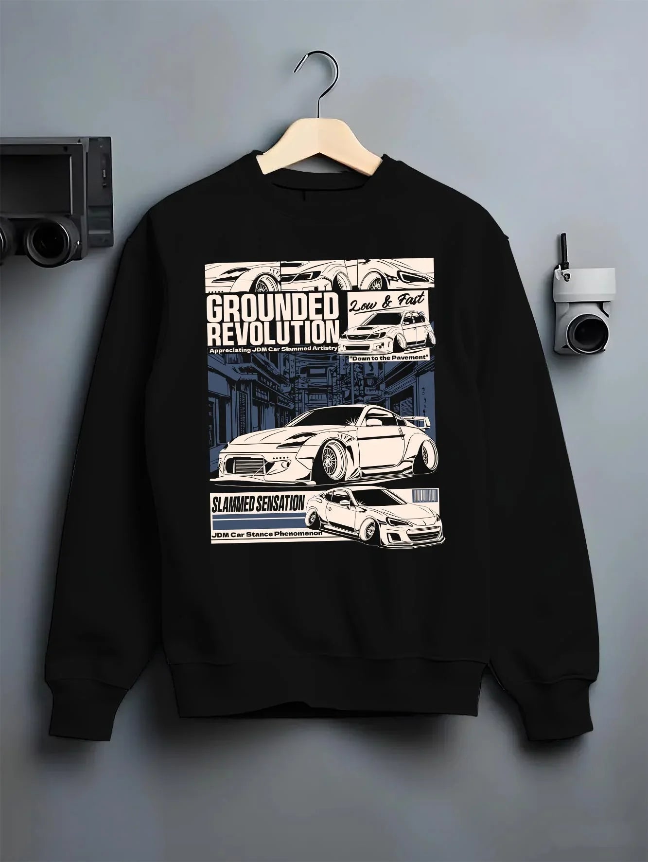 Black crewneck sweatshirt on a hanger against a grey wall, featuring EVO drift jdm japanese stance slammed street racing graphic.