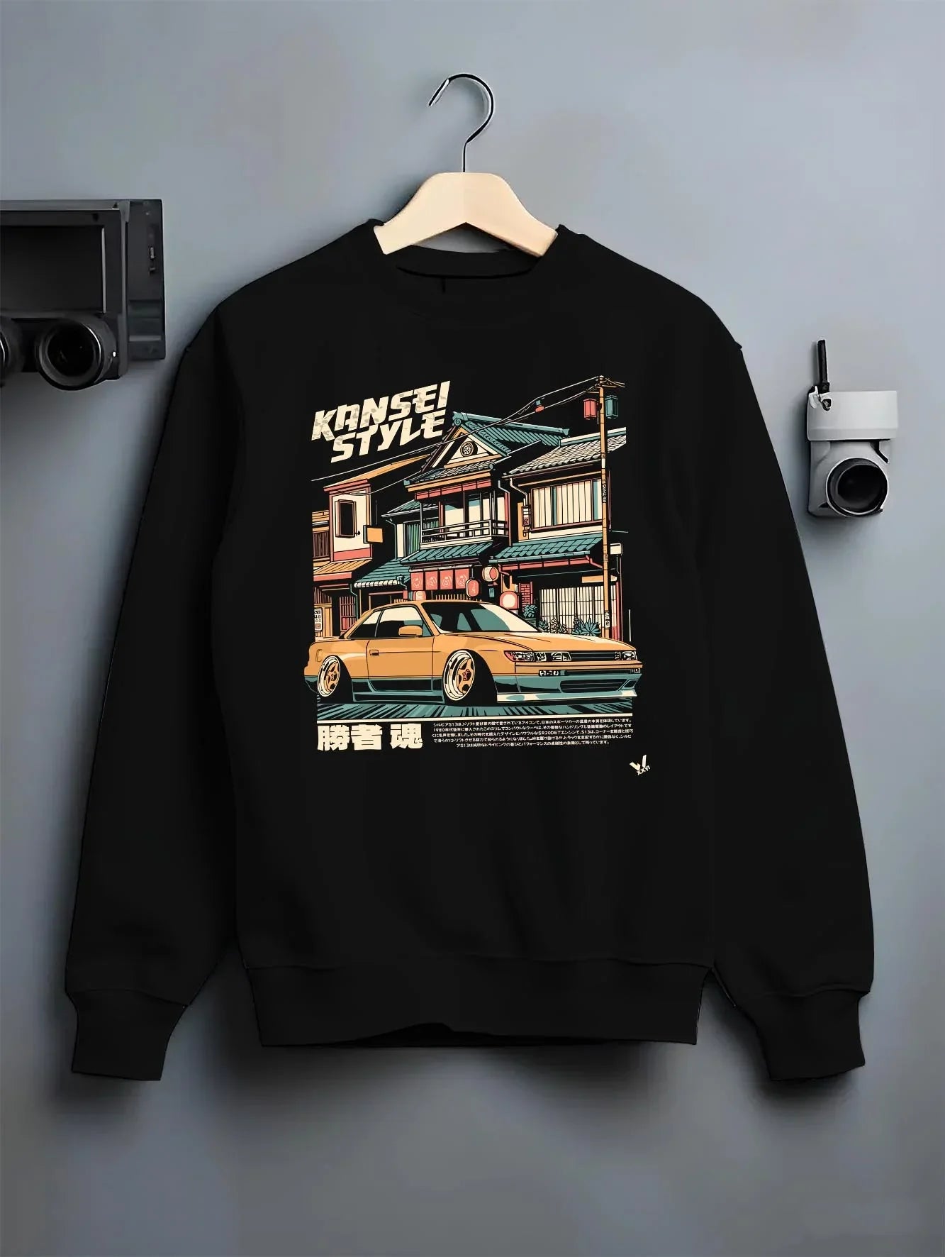 Black crewneck sweatshirt on a hanger against a grey wall, featuring racing drift jdm japanese street performance kansei.