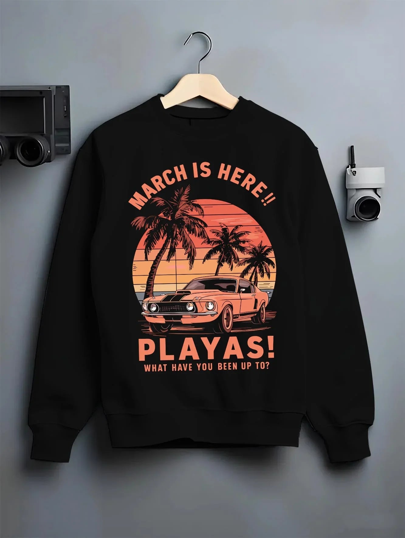 Black crewneck sweatshirt on a hanger against a grey wall, featuring STI street racing performance motorsport automotive playas.
