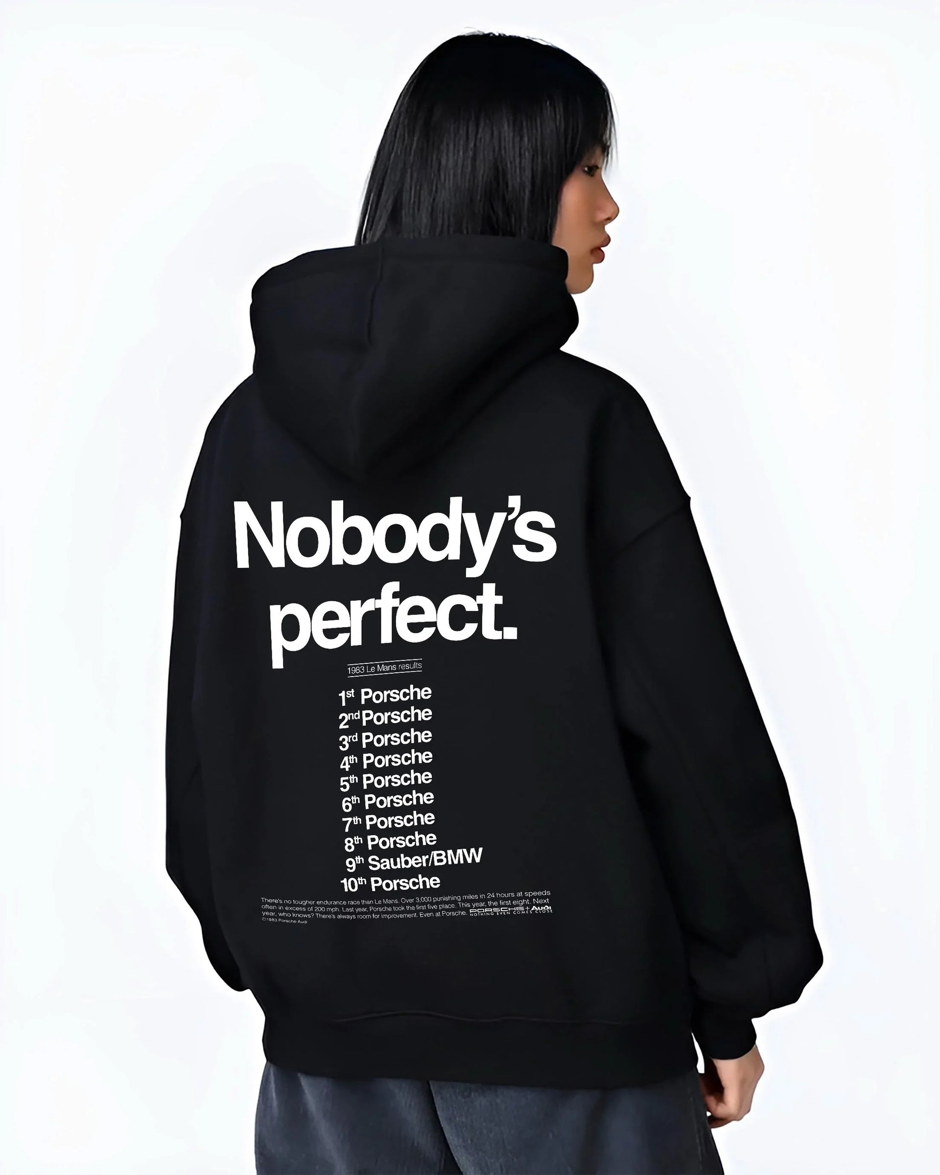 Black hoodie worn by a female model, back view, featuring Porsche rs racing le mans motorsport street performance graphic.