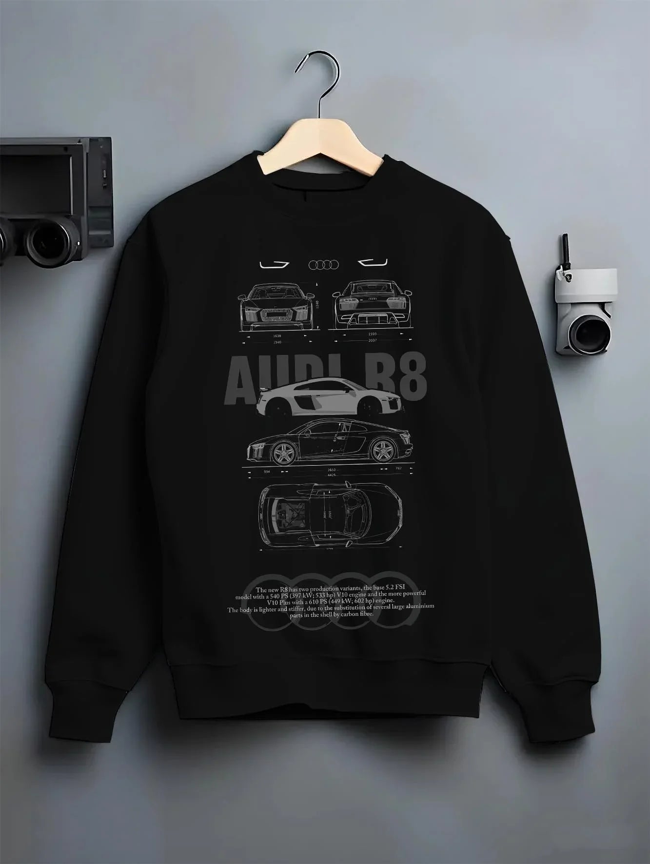 Black crewneck sweatshirt on a hanger against a grey wall, featuring Audi R8 v10 euro enthusiast racing street performance graphic.