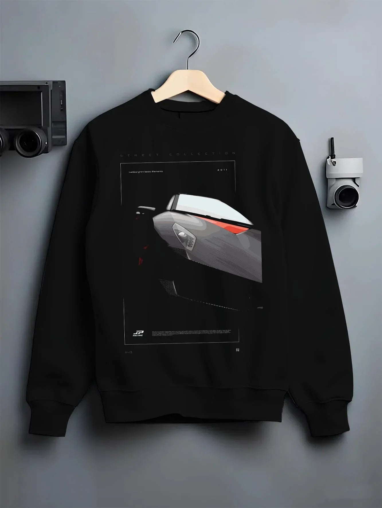 Black crewneck sweatshirt on a hanger against a grey wall, featuring Lamborghini racing street enthusiast performance graphic.